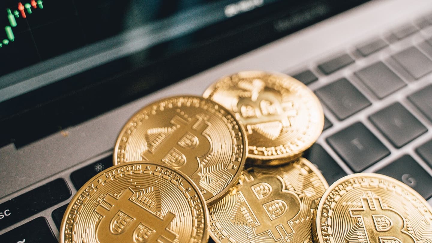 Physical bitcoin token resting on a financial newspaper